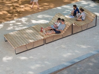 A long wooden bench with curves to create multiple seating positions.