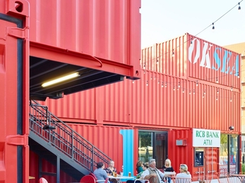 Red shipping containers and wooden benches make up a proposed community hub