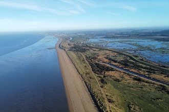 An aerial view of Wild Ken Hill, showing The Wash estuary area on a sunny day against a blue sky.