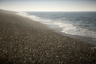 Shingle beach and blue waves at Cley Marshes