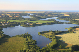 A drone image of a Broad on a sunny day, including patches of green land around it