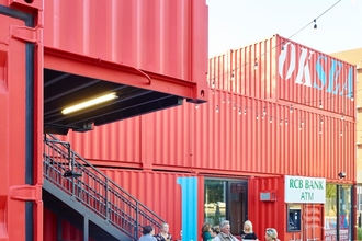 Red shipping containers and wooden benches make up a proposed community hub