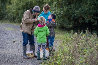 A family at a nature reserve wearing hats, wellies and gloves. 