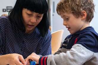 Alice Lee helping a child make a mobile