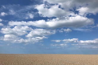 Cley shingle beach on a sunny day with fluffy white clouds