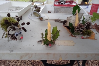 Christmas crafts made from clay and natural materials sit on a white table