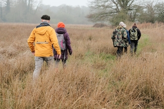 Four people walking through a field in winter