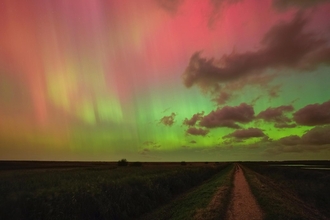 Intense swathes of pink and green light up the sky above the East Bank at Cley Marshes