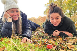 Two women look delighted as they spot a fly agaric