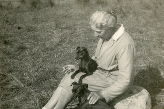 Picture of photographer Emma Turner sitting on the grass with two dogs.