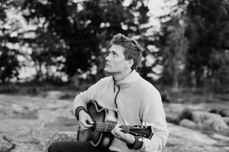 Monochrome picture of Merlyn Driver playing his guitar.