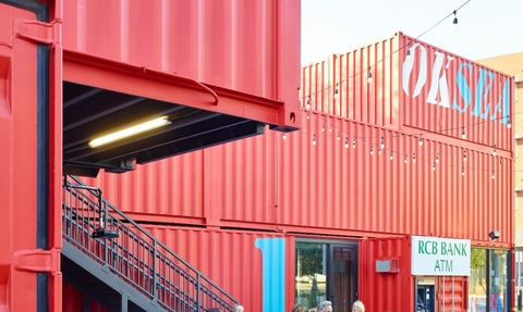 Red shipping containers and wooden benches make up a proposed community hub