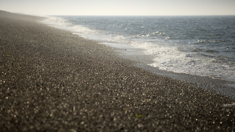 Shingle beach and blue waves at Cley Marshes