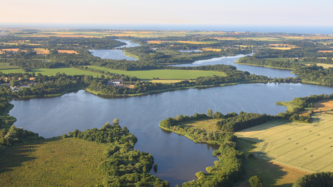 A drone image of a Broad on a sunny day, including patches of green land around it