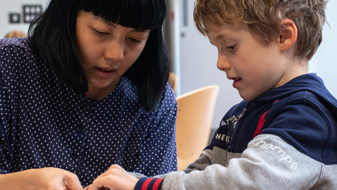 Alice Lee helping a child make a mobile