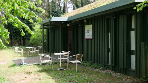 The moss-topped visitor cenre at Weeting heath on a sunny day with tables and chairs outside it