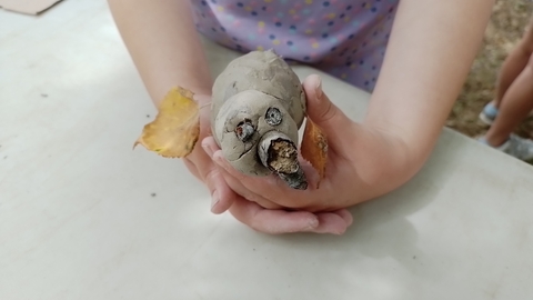 A child's hands holding a clay craft animal