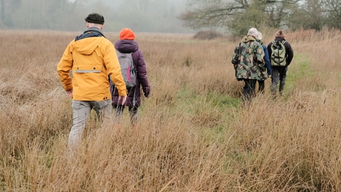 Four people walking through a field in winter