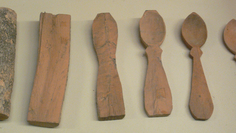 Six pieces of wood next to each other progressively carved starting with a small branch covered in bark to a completed carved spoon on the right