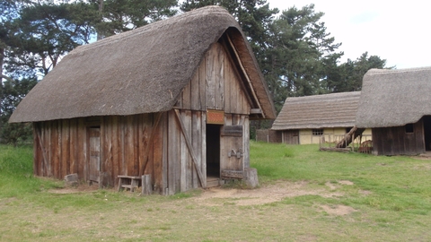 Several small thatched and timbered buildings in a Suffolk field