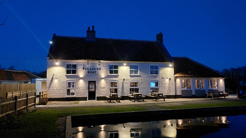 a view of the Pleasure Boat inn at night with the reflection in the water