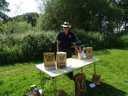 At Hickling, a man displays his carvings of swallowtail butterflies made out of bits of log. 
