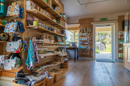 The gift shop at Cley. There are tote bags, books, mugs and more on the shelves.