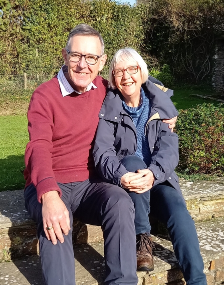 A man and woman sit together, smiling in the sun