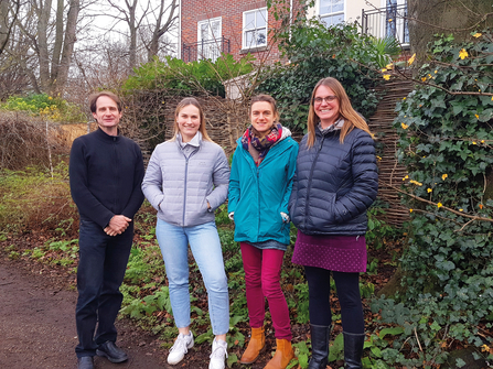 Four members of NWT staff smiling outdoors in raincoats. 