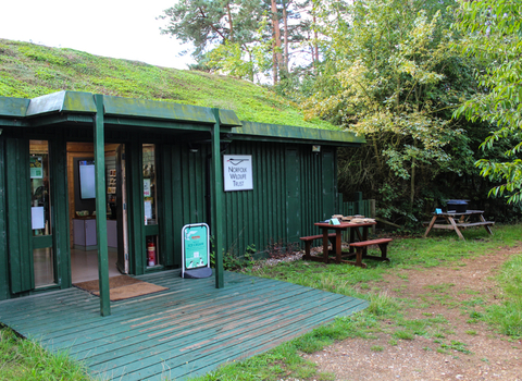 The green moss-topped Weeting Heath visitor centre, with benches outside