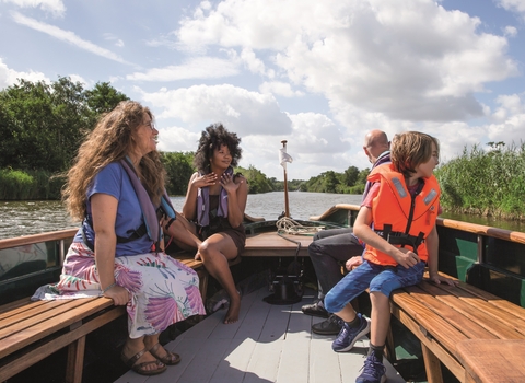 A group of adults and young people enjoying a boat trip on Ranworth Broad