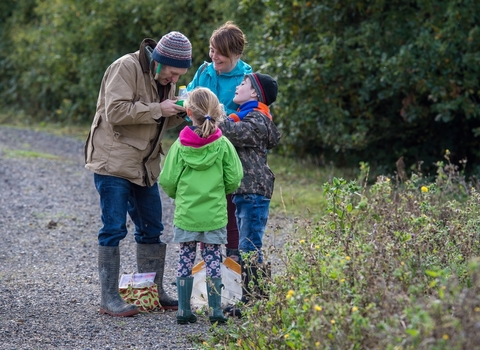 A family at a nature reserve wearing hats, wellies and gloves. 