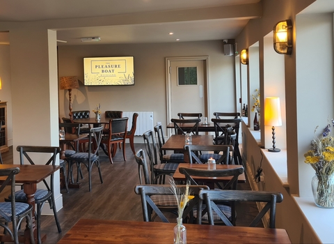 Tables, chairs, warm lamps and flowers inside the Pleasure Boat Inn.