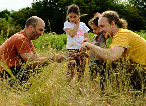 two men and children looking at grass